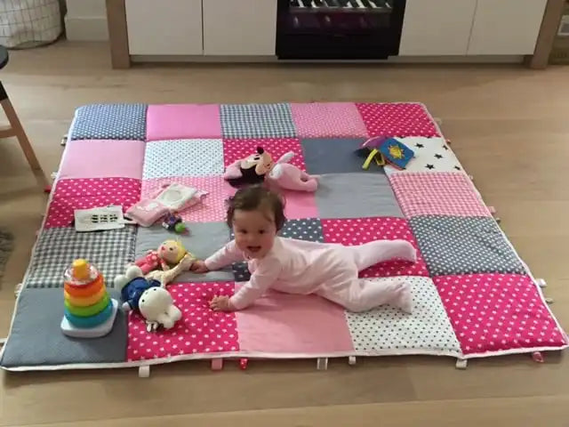 Een baby die kruipt op een kleurrijk, patchwork speelmat.