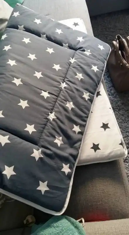 Een gestikte deken met witte sterren op een donkergrijze achtergrond.