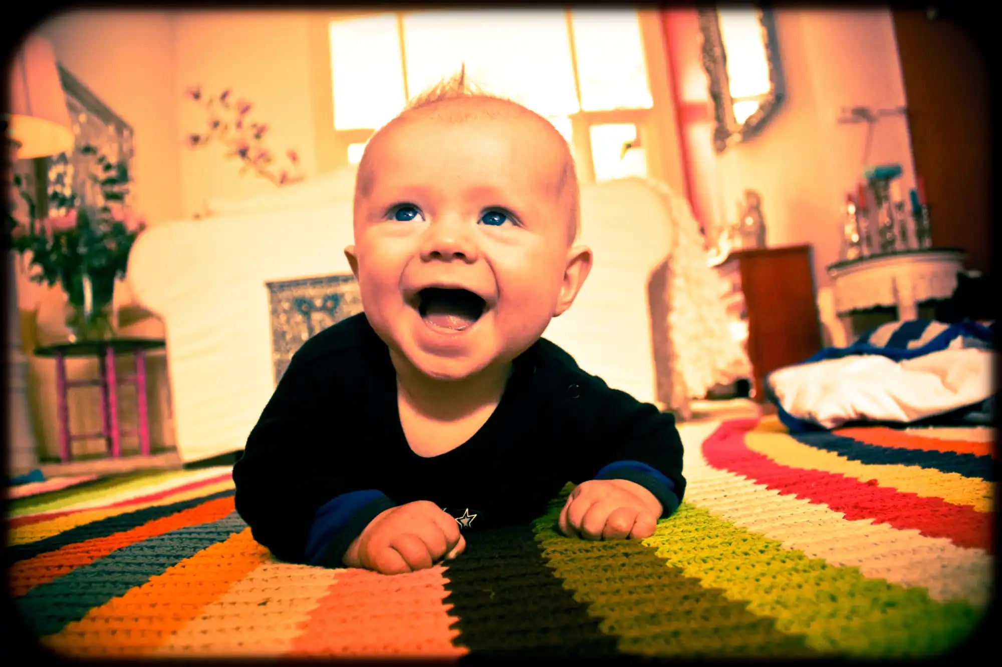 Een gelukkige zuigeling met een lichte mohawk en heldere blauwe ogen, draag een zwart shirt met blauwe boorden.