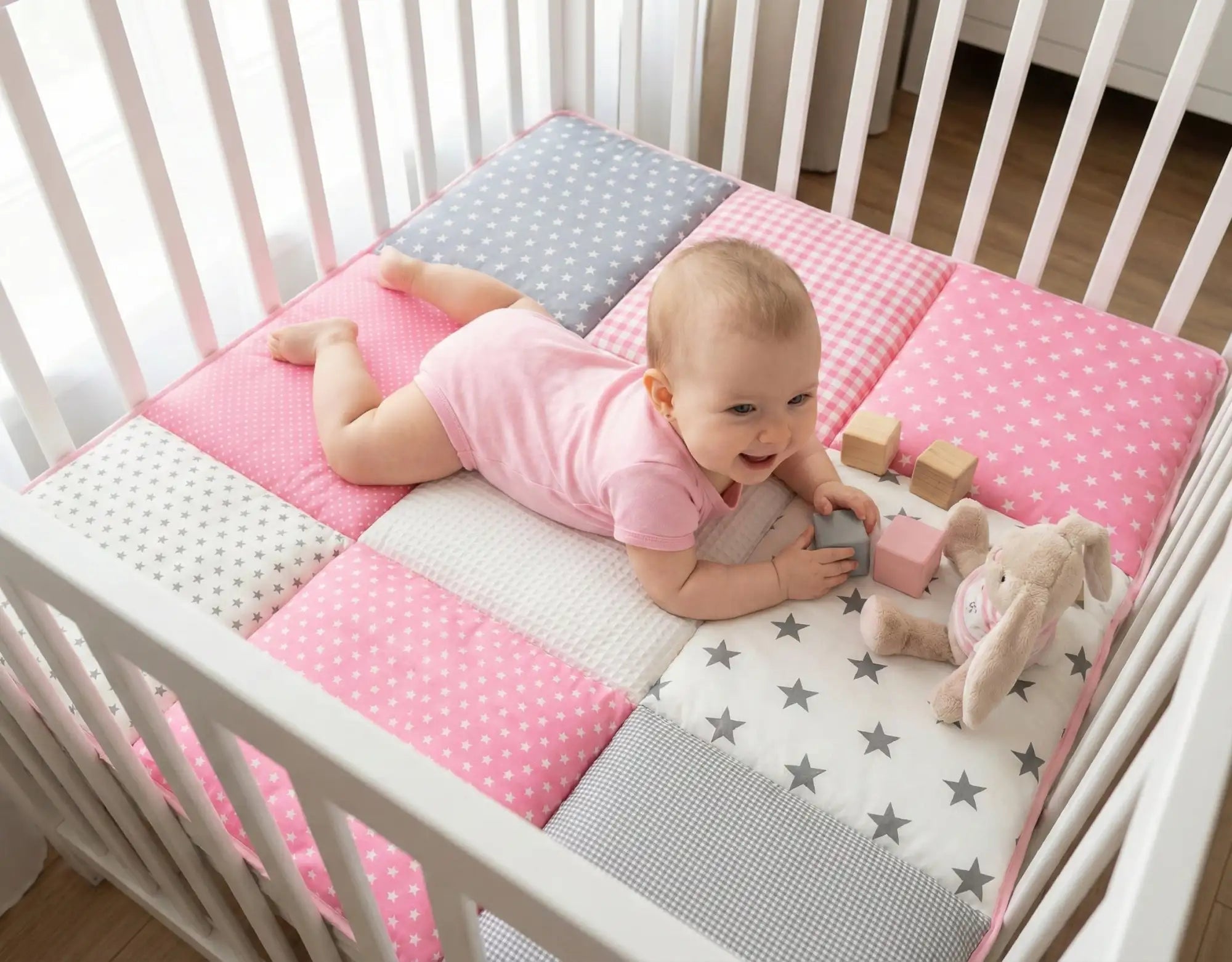 Roze en grijze sterrenpatroon kinderbedomranding met een patchworkontwerp met stippen, geruit en effen texturen.