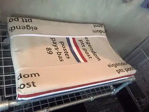 Een beige stoffen matras of kussen met rode, witte en blauwe strepen.