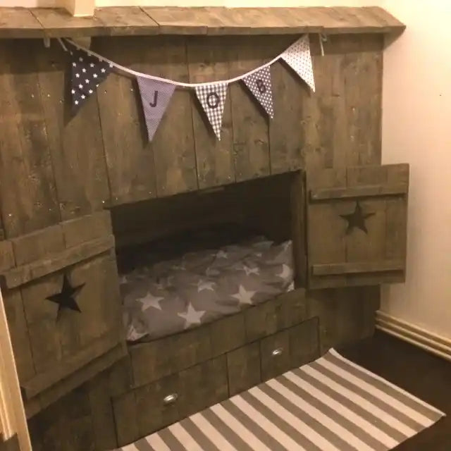 Een houten kinderbed met een geïntegreerd speelhoekje en opberglades.