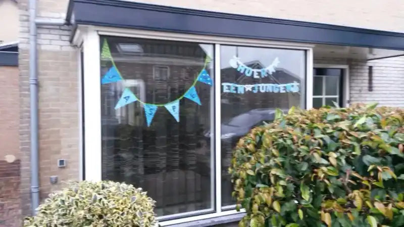 Een huiskozijn versierd met een blauwe en groene banner.